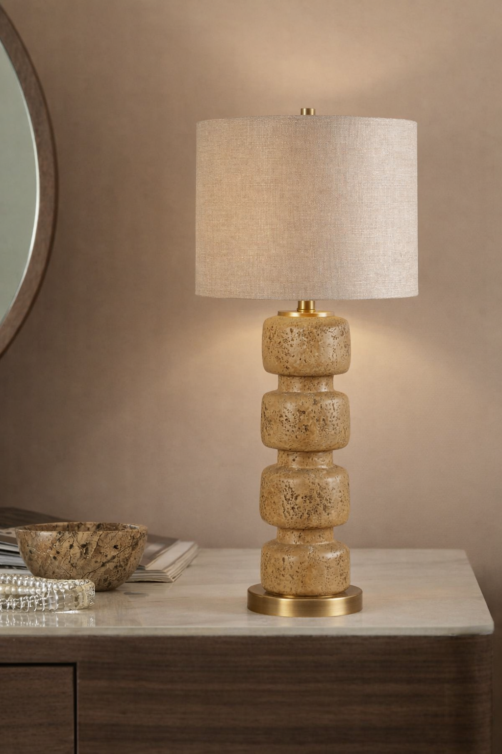 Table lamp with a textured ceramic base and beige fabric shade on a wooden surface.