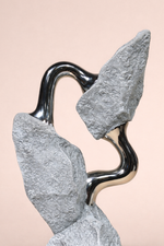 Abstract sculpture with wavy black and gray forms on a beige background