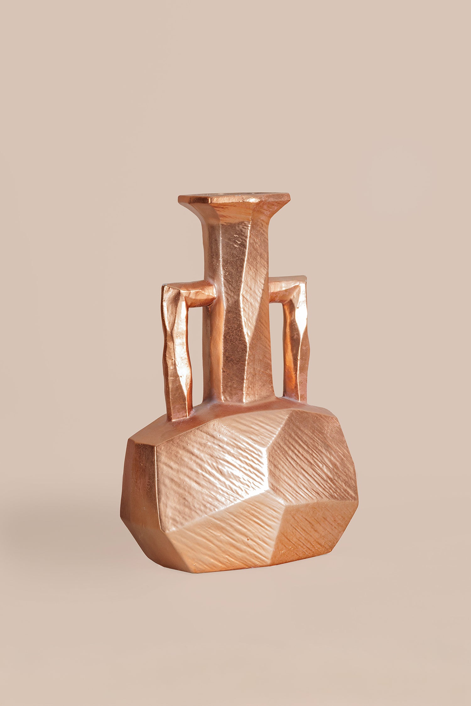 Bronze vase with geometric design on a beige background