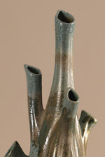 Bronze sculpture with multiple cylindrical protrusions on a beige background