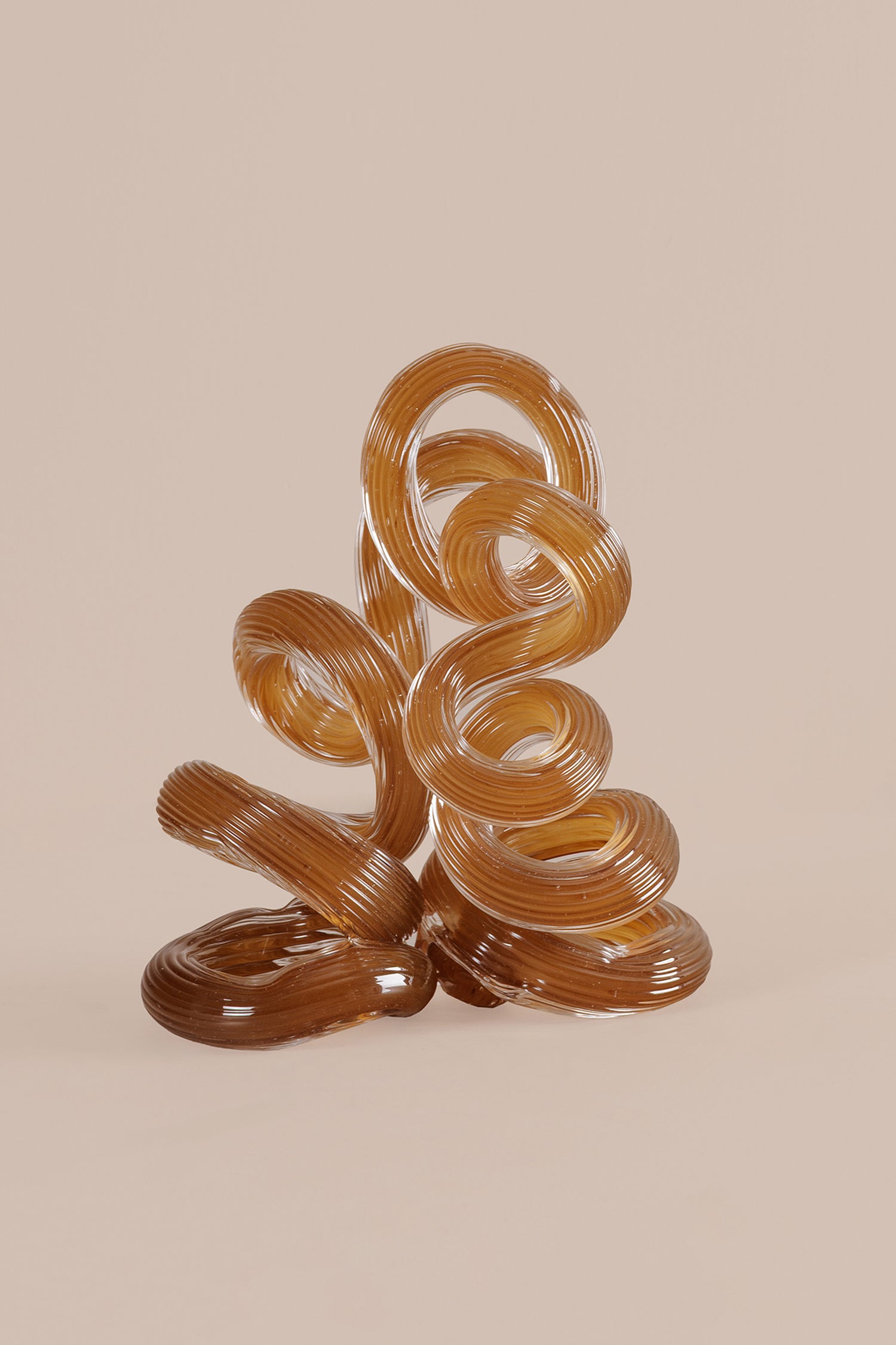 Decorative glass sculpture with wavy design on a beige background