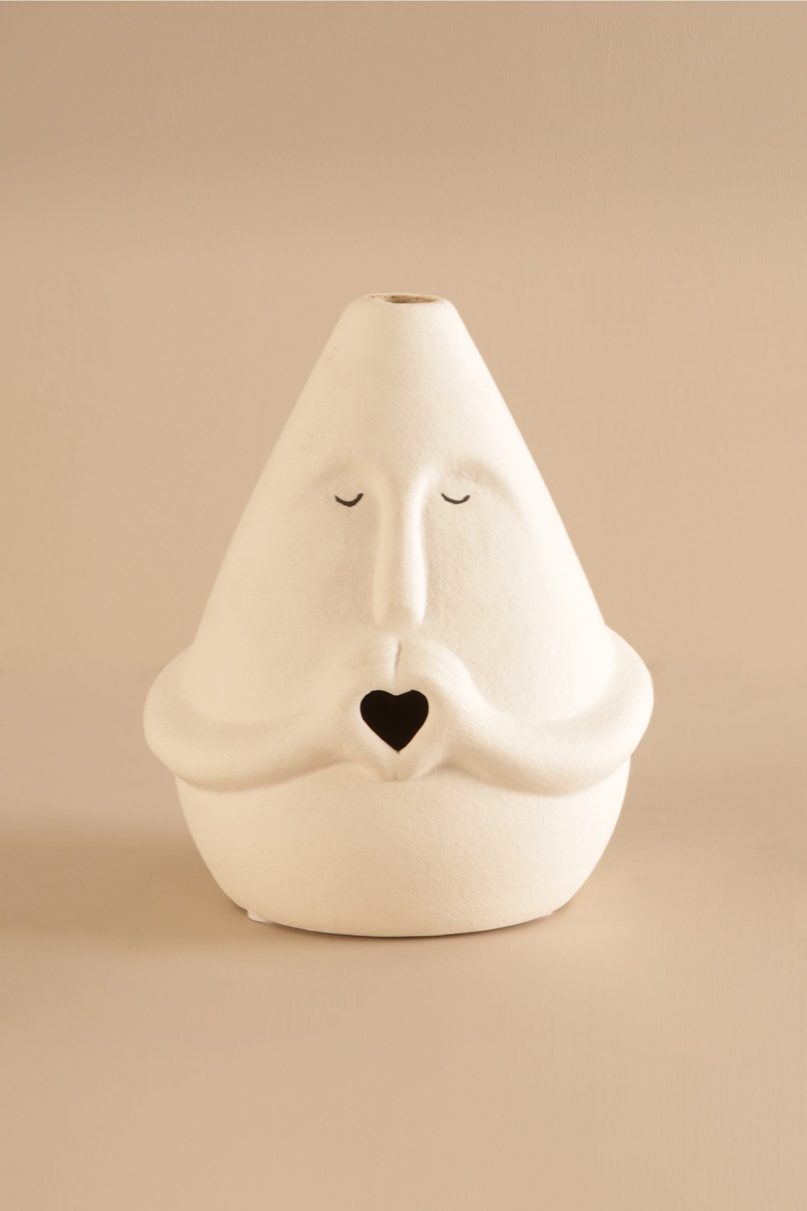 Matte off-white ceramic sculpture showing facial details and heart-shaped opening