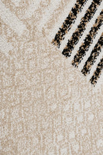Close-up of a textured area rug in cream and beige with a pattern of black and beige diagonal stripes in the upper right corner.