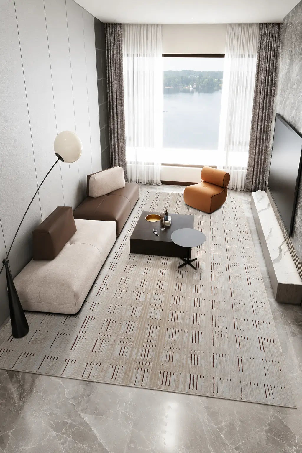 A modern living room featuring a large patterned area rug in beige and gray, styled with a cream and brown sectional sofa, a dark wood coffee table, a black floor lamp, and a large window overlooking a body of water.