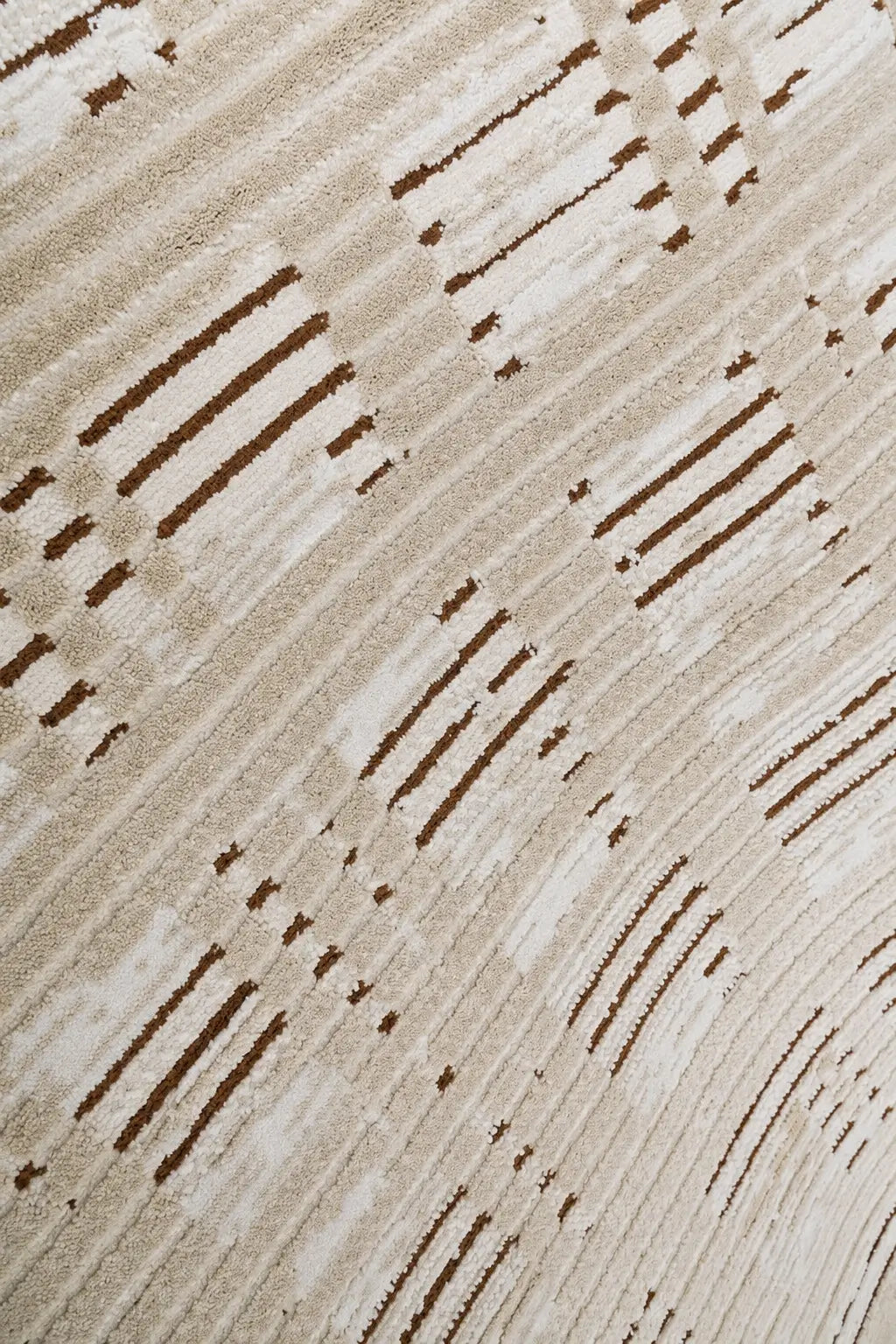A close-up of a textured area rug featuring a modern abstract pattern of diagonal lines and dotted accents in dark brown on a warm beige and cream background.