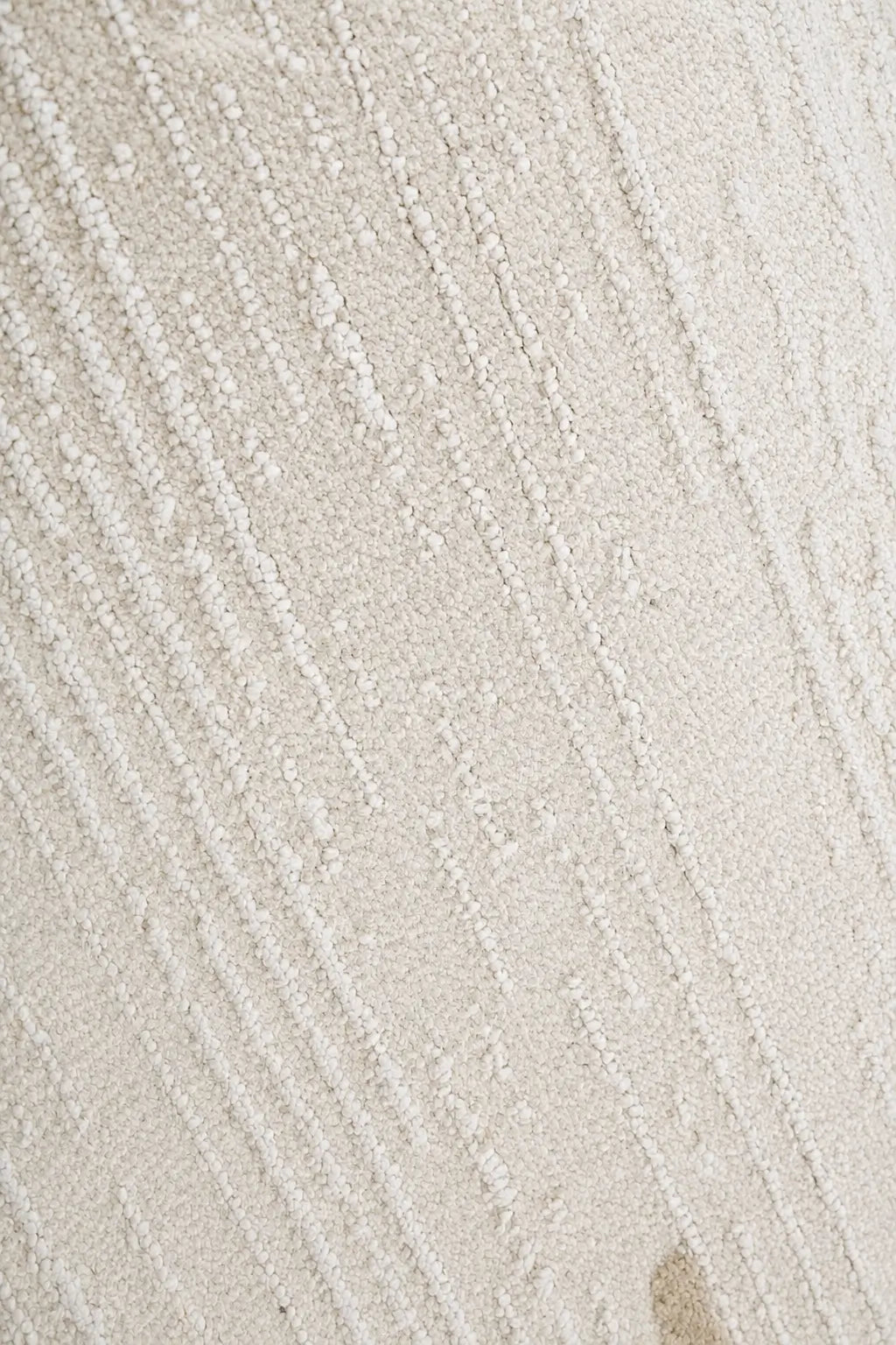 A close-up of a textured cream or off-white fabric with a raised, ribbed vertical stripe pattern.