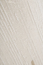 A close-up of a textured cream or off-white fabric with a raised, ribbed vertical stripe pattern.
