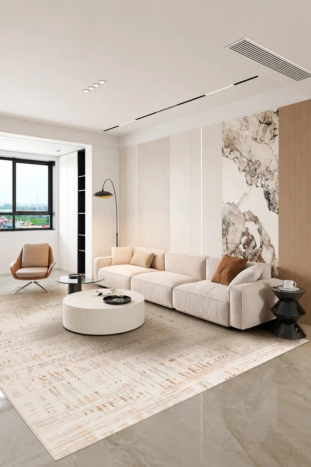 A modern living room featuring a light beige sectional sofa, a round white coffee table, a large textured beige rug, and a prominent vertical wall art mural with a black and white abstract pattern.