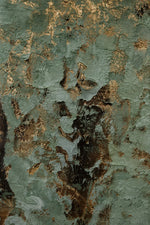 Abstract textured artwork featuring a distressed, peeling paint surface in muted sage green, gray, and metallic gold-brown tones.