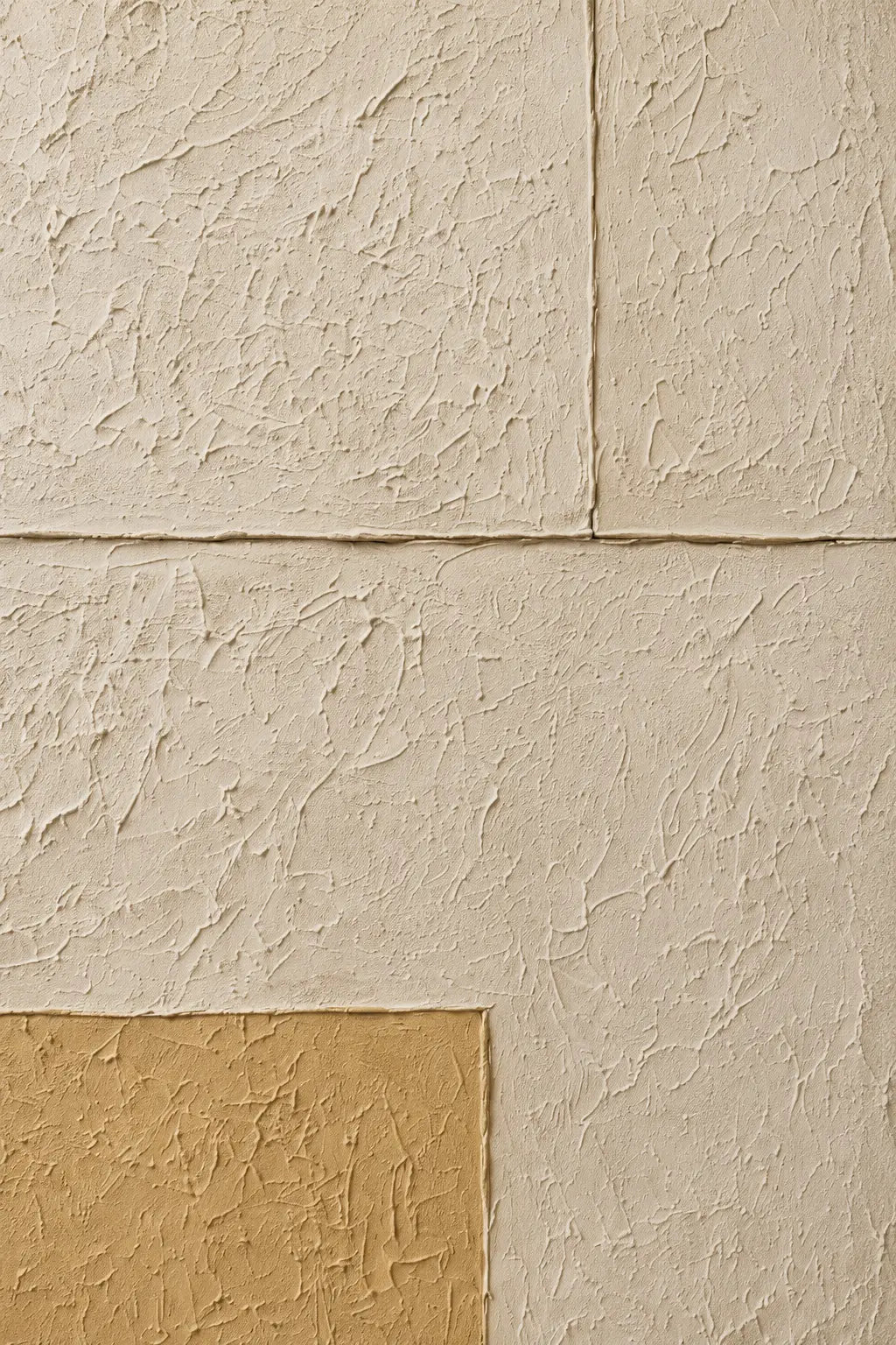 Textured wall panels in warm beige and cream tones with a stucco-like finish, arranged in a geometric layout with one tan panel in the lower left corner.