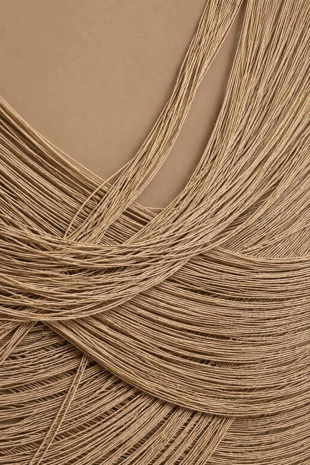A close-up of fine tan and light brown hair strands arranged in soft curls and waves against a solid tan background.