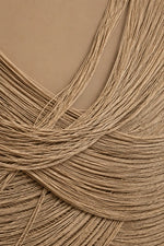 A close-up of fine tan and light brown hair strands arranged in soft curls and waves against a solid tan background.