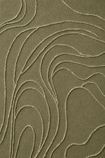 A close-up of a textured fabric or wallpaper in a muted olive green color, featuring a raised abstract wavy pattern in a contrasting light beige tone.