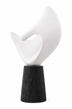An abstract sculptural tabletop piece featuring a smooth, curved white top section mounted on a textured, tapered black base, shown against a plain white background.