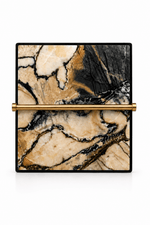 A square clutch bag featuring a beige and black marble pattern, accented by a horizontal gold metal bar across the center and a slim black border.