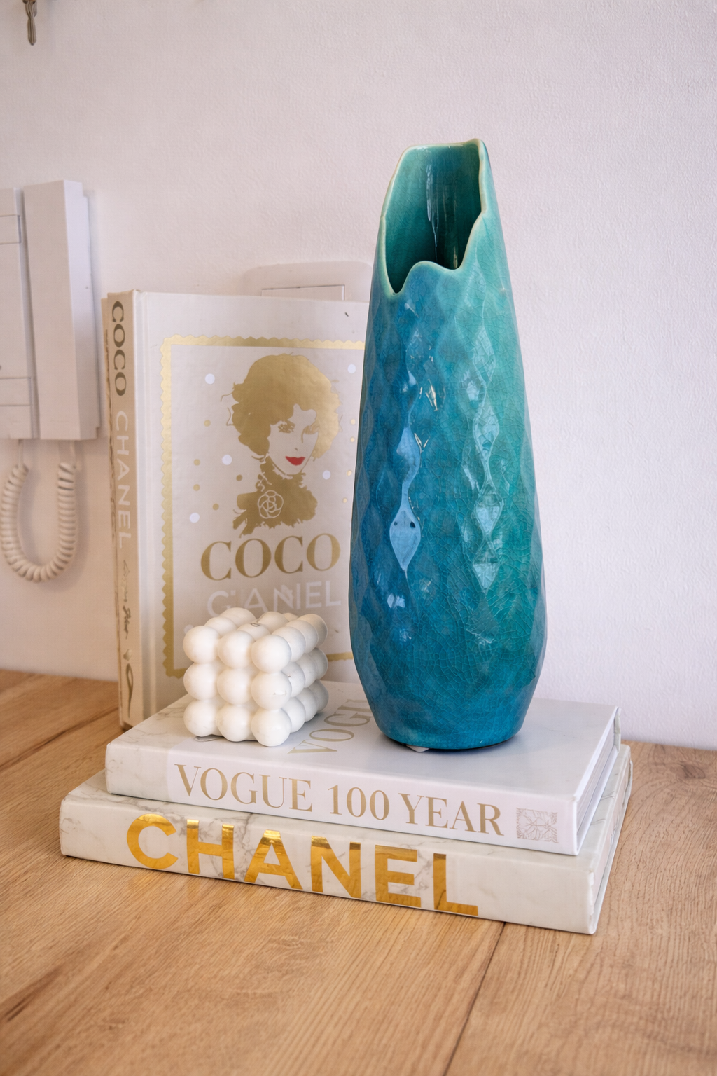 Teal vase on top of books with a decorative background