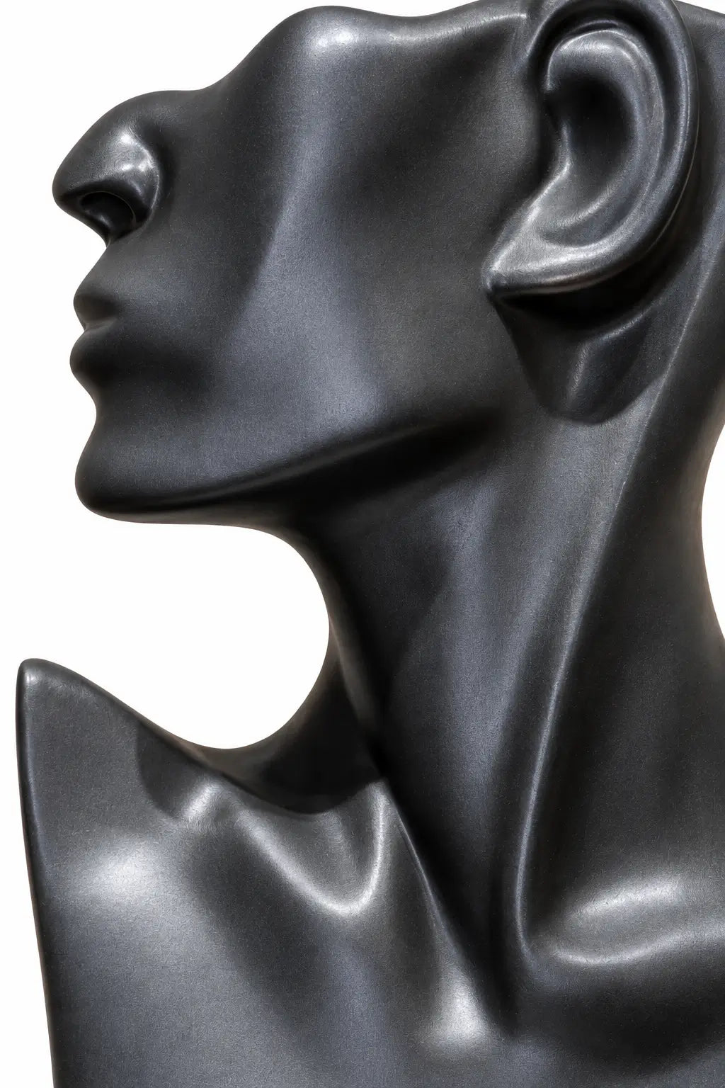 A close-up side profile of a glossy black sculptural bust or mannequin head on a plain white background.
