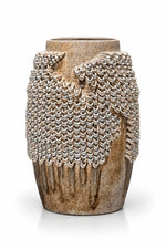 A rustic ceramic vase with a textured, ribbed brown base and a draped, woven chainmail-style overlay in beige and gray tones, set against a plain white background.