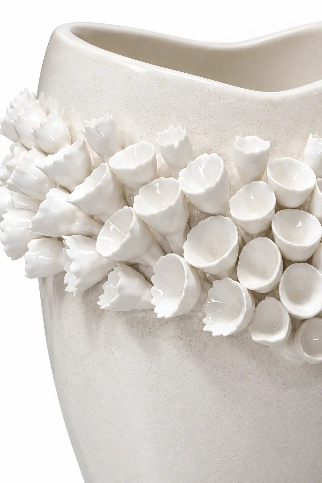 A close-up of a white ceramic vase featuring a textured, organic shape adorned with a dense cluster of sculpted, 3D flower buds around the upper portion.