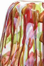 Close-up of a glossy ceramic vase featuring a watercolor drip pattern with red, green, brown, pink, and white paint on a white base.