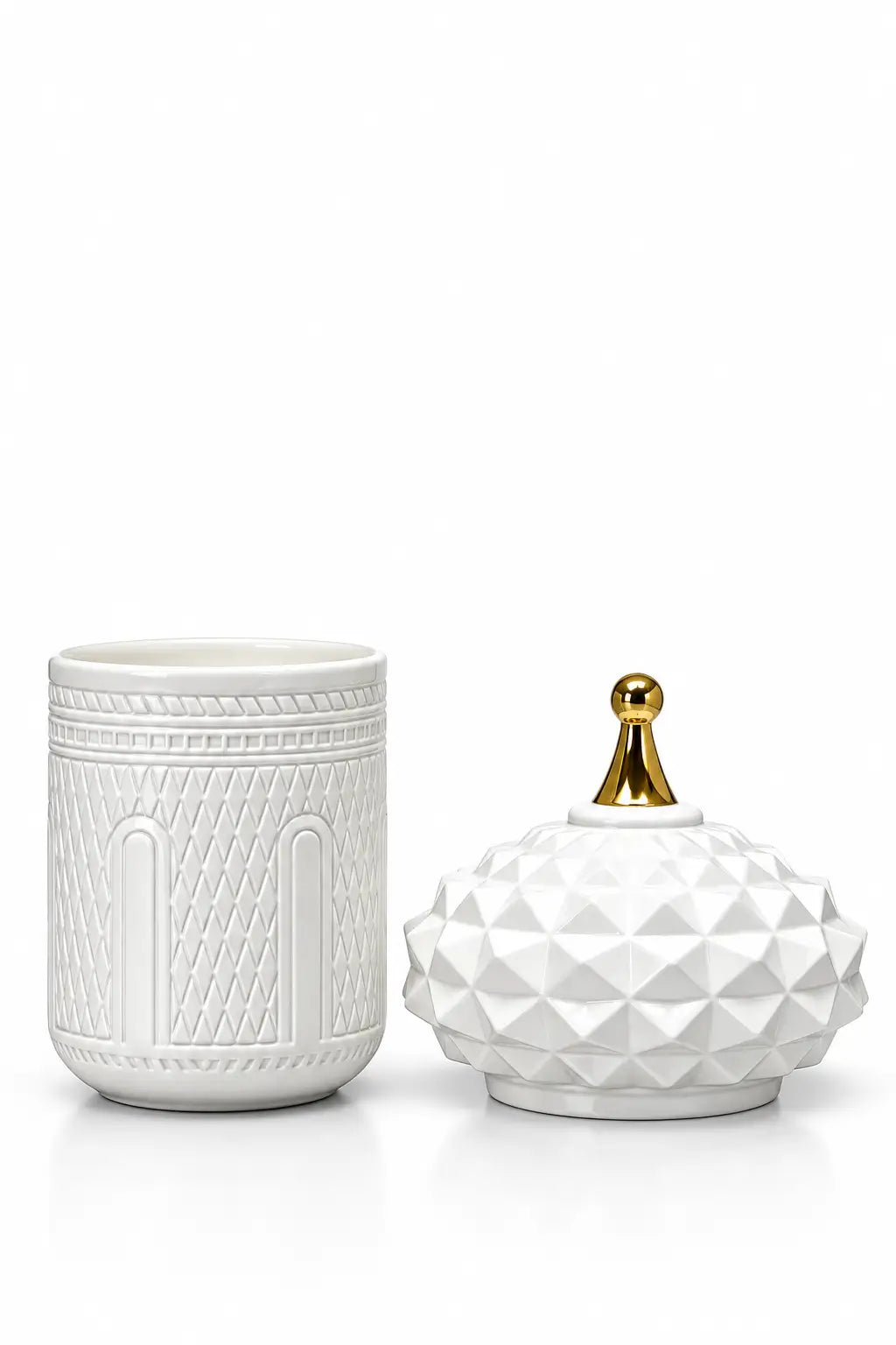 A white ceramic candle holder and matching lid set on a white background. The holder features a textured geometric pattern, and the lid has a faceted diamond texture with a small gold finial on top.