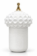 A white ceramic lidded container with a faceted, geometric textured lid and a small gold finial on top, set against a plain white background.