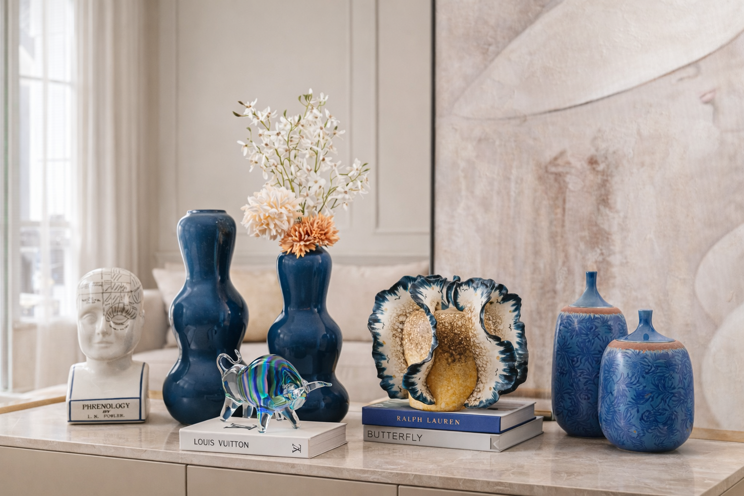 Decorative items including vases, sculptures, and books on a surface with a neutral background.