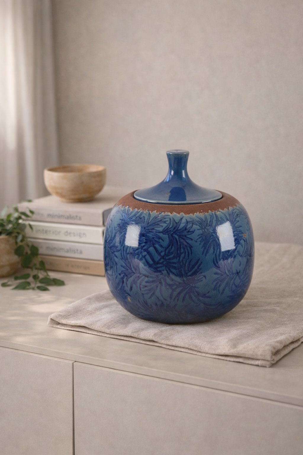 Blue ceramic jar with a brown base on a light surface