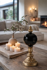Decorative candle holder on a wooden table with candles and a vase in a living room setting.