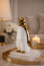 Decorative penguin figurine on books with a candle and lamp in the background