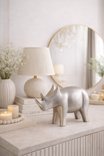 Decorative rhinoceros figure on a shelf with a lamp and books in a bright room.