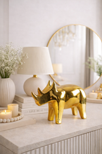 Gold rhinoceros figurine on a decorative table with books, candles, and a lamp.