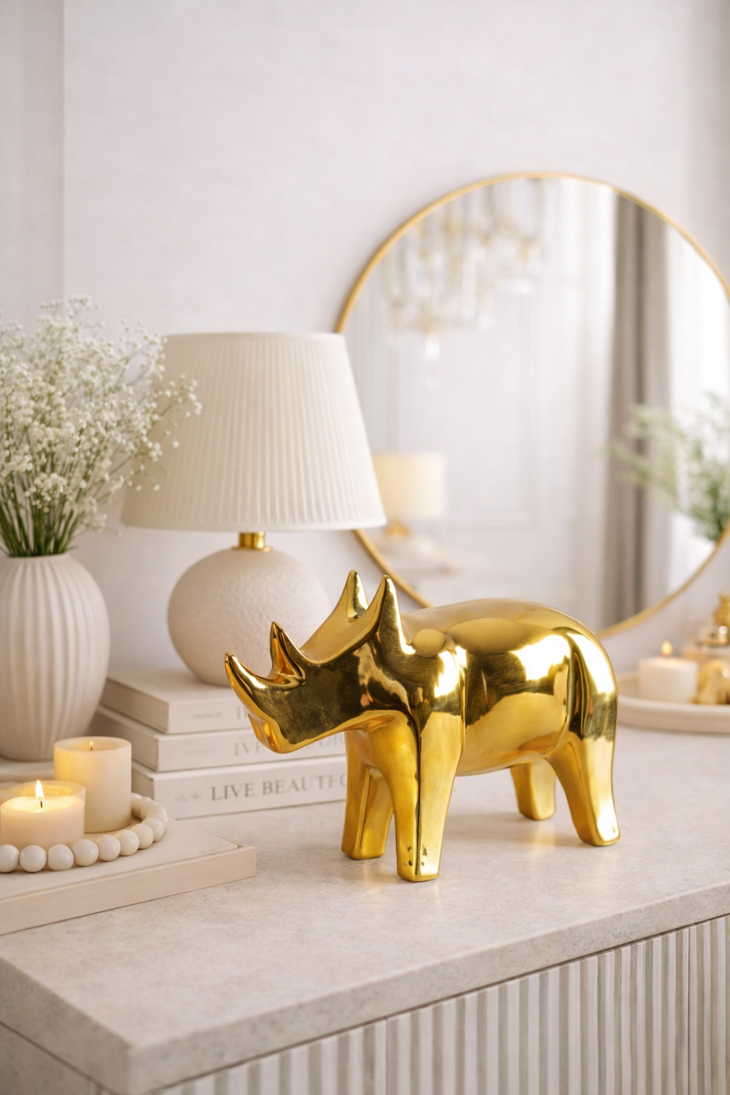 Gold rhinoceros figurine on a decorative table with books, candles, and a lamp.