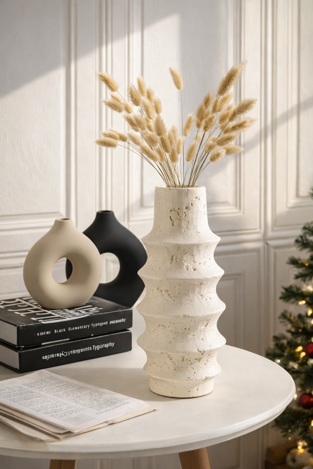 Decorative vase with dried plants on a table against a wall with paneling.