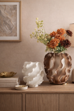 Decorative vases and a lamp on a wooden surface with a neutral wall background