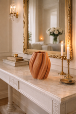 vase on a marble surface with a large mirror reflecting a candlelit room.