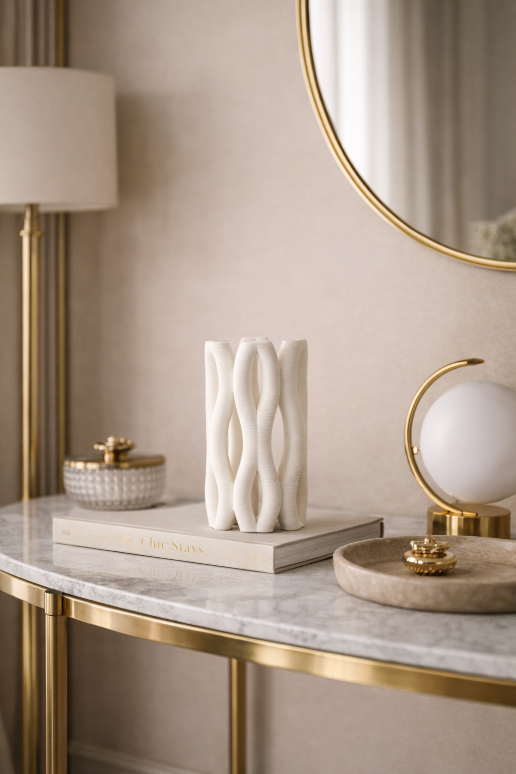 Decorative items on a marble table with gold accents against a beige wall.