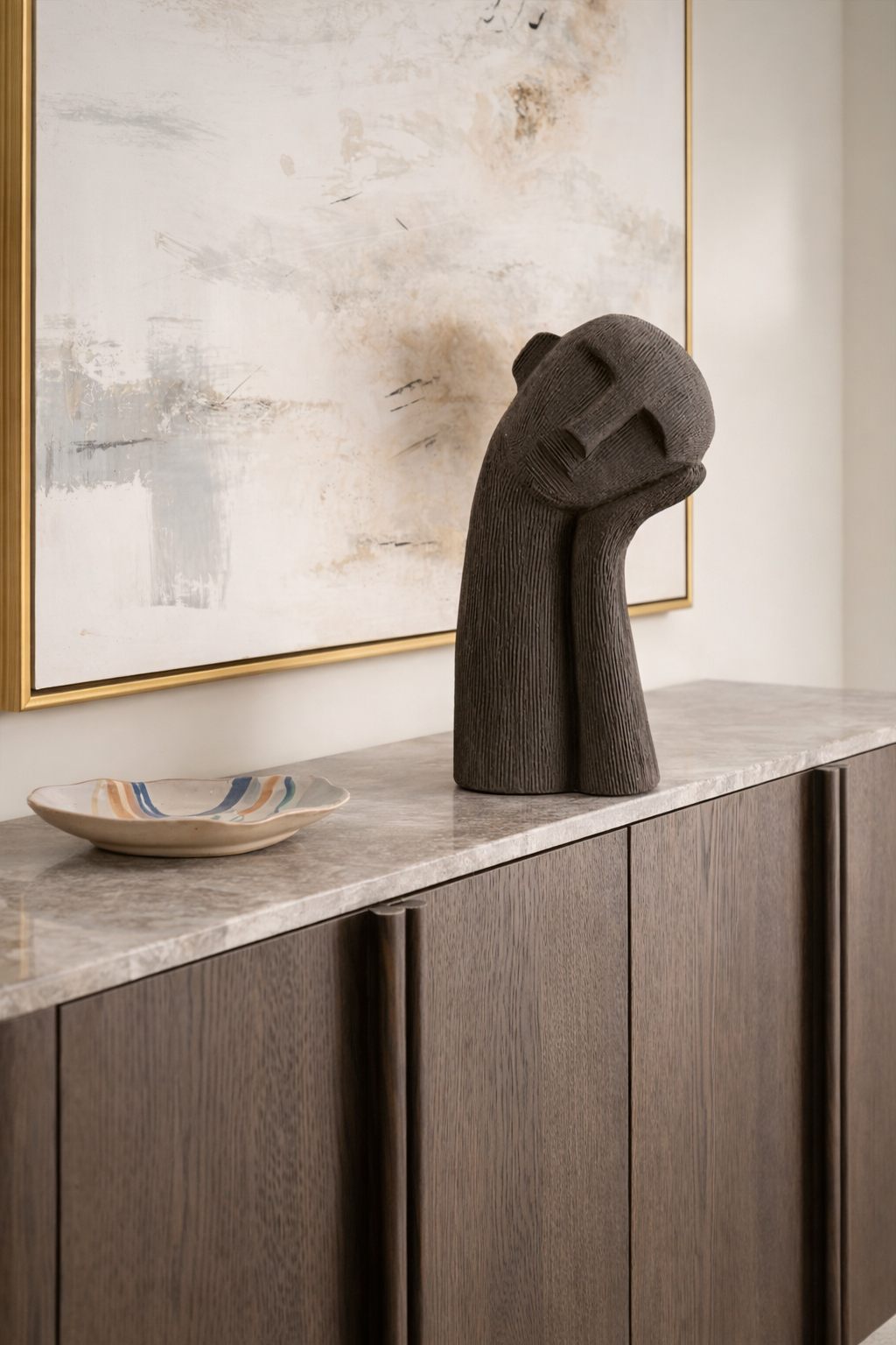 Decorative sculpture on a marble countertop with a framed abstract painting in the background.