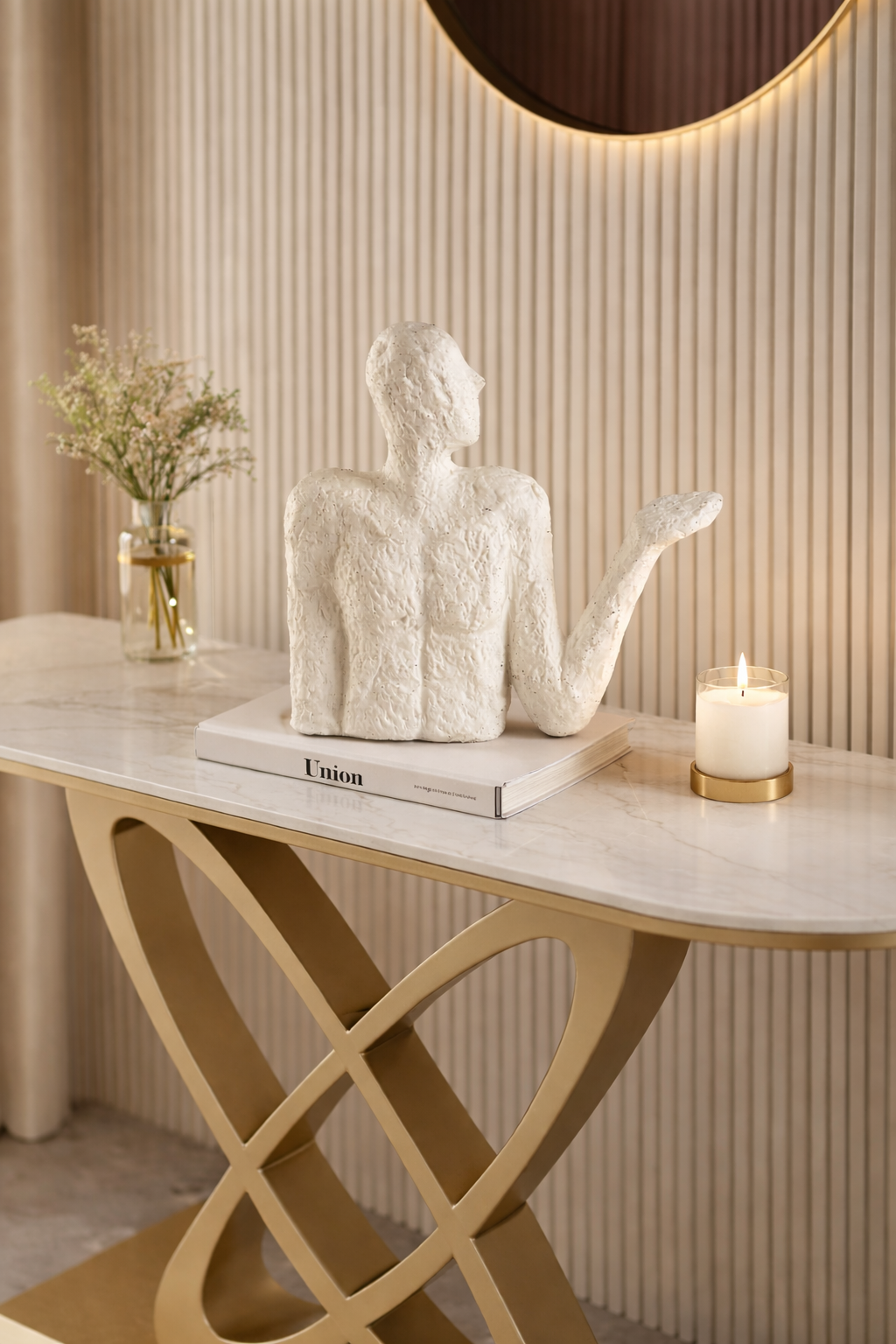 Decorative table with a textured sculpture, candle, and book against a striped wall.