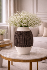 Decorative vase with knitted cover on a marble table in a living room setting