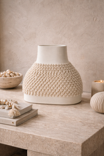 Decorative ceramic vase with textured design on a wooden surface.
