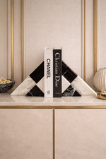 Decorative bookends with Chanel and Christian Dior branding on a stylish shelf.