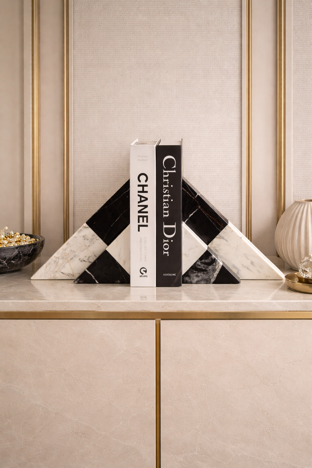 Decorative bookends with Chanel and Christian Dior branding on a stylish shelf.