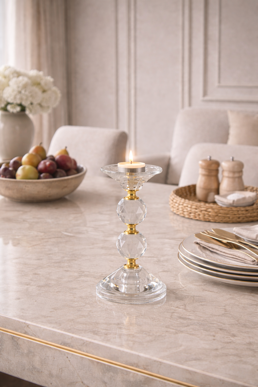 Decorative candle holder on a table with fruit bowl and plates in a stylish room.