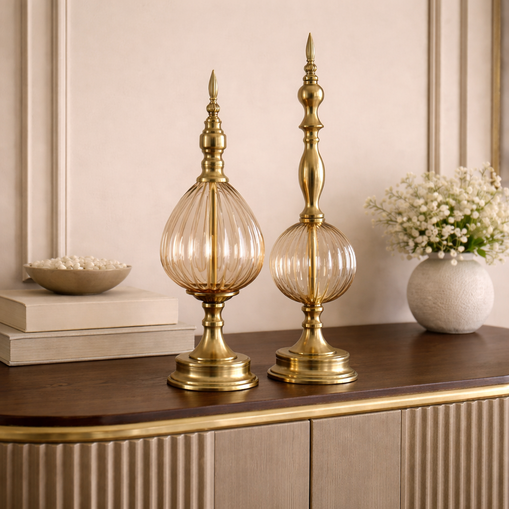Two gold decorative vases on a wooden surface with a neutral background