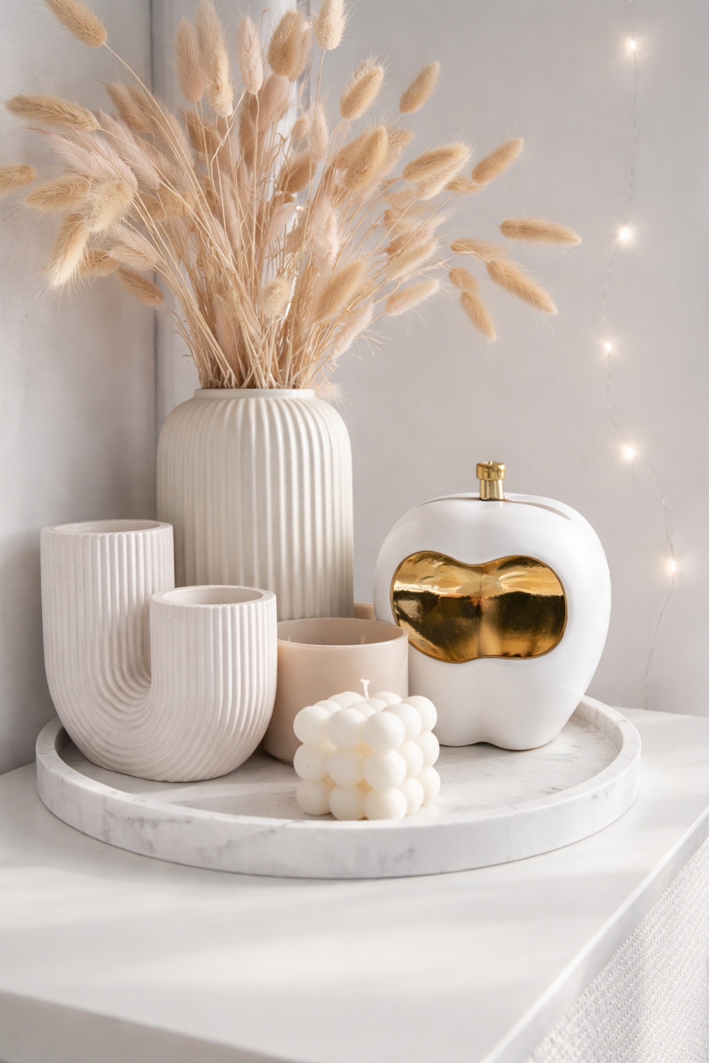 Decorative arrangement of ceramic vases and a gold-adorned white vase on a marble tray.