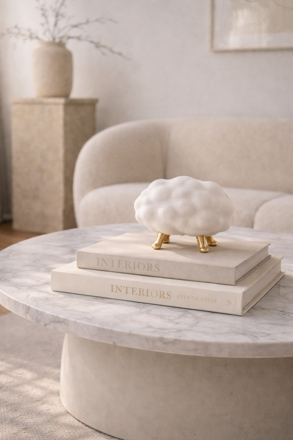 Decorative white sculpture on books on a marble coffee table with a neutral background