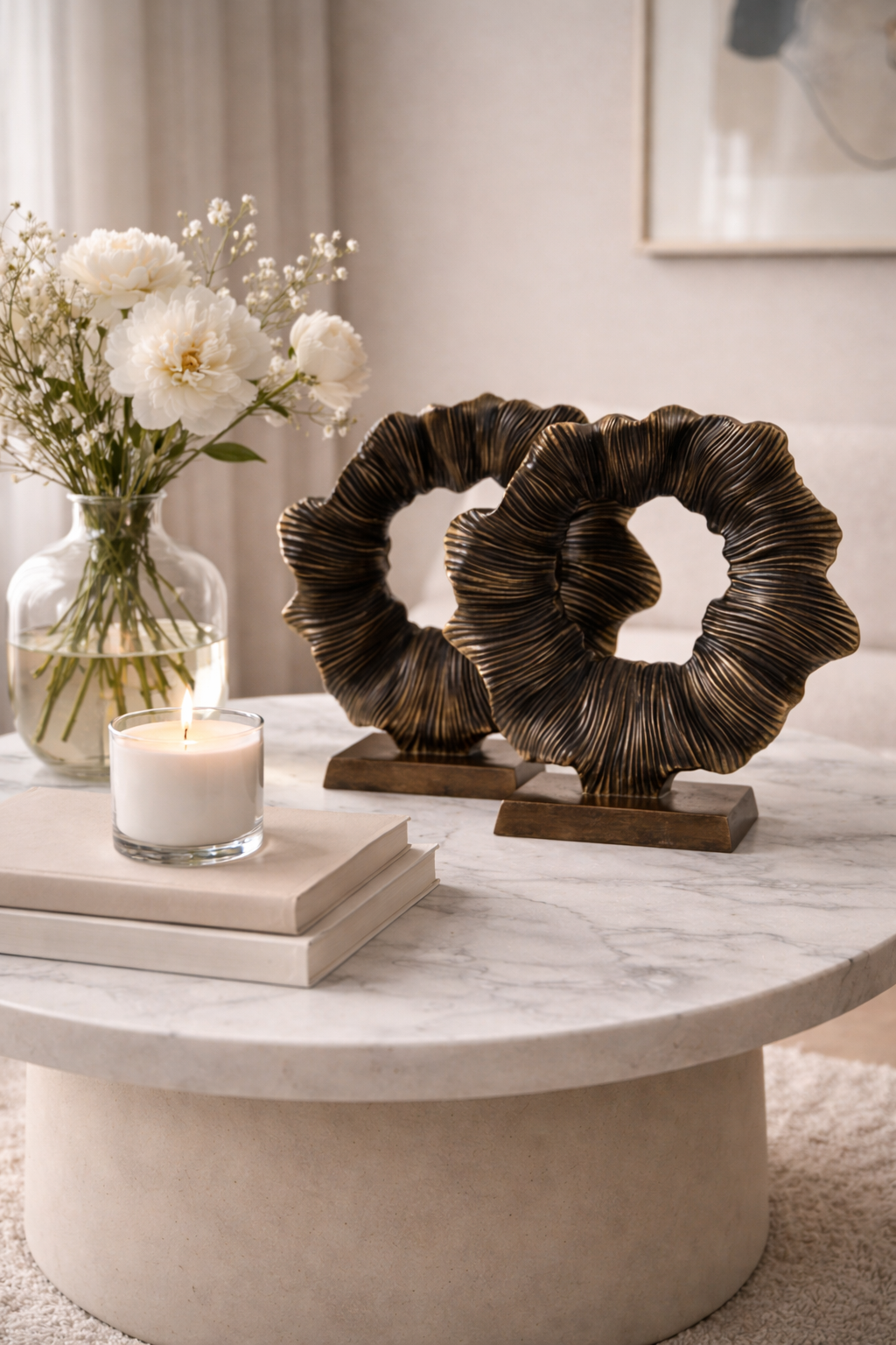 Decorative table with a candle, books, and a decorative metal piece.