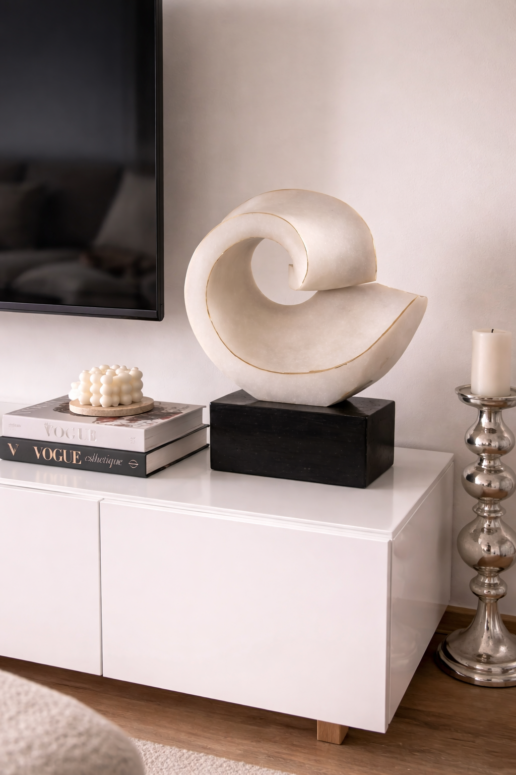 Decorative sculpture on a white cabinet with books and a candle in the background