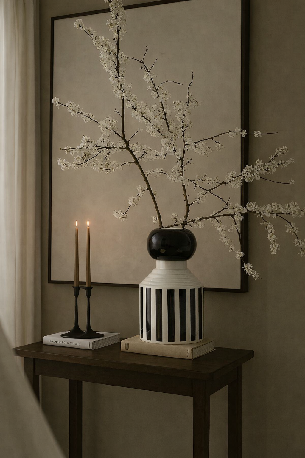 Decorative vase with branches on a table against a wall with framed art